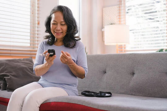 A_senior_woman_s_hand_checking_her_blood_sugar_level_with_a_glucometer_by_herself_at_her_home..jpg